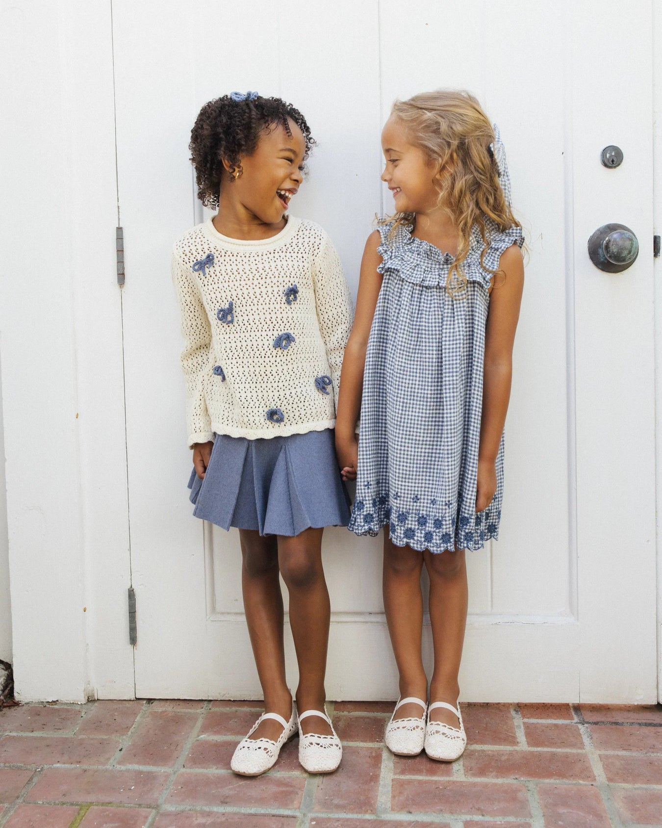 two girls side by side smiling wearing blue skirts and dresses