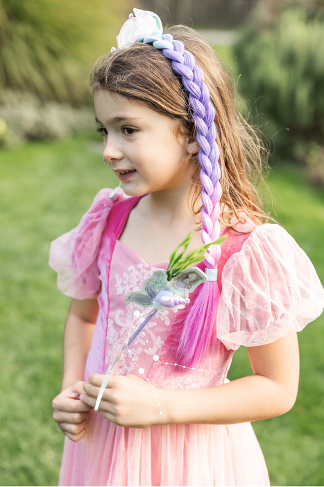 Young girl in a pink dress with a colorful headband outdoors