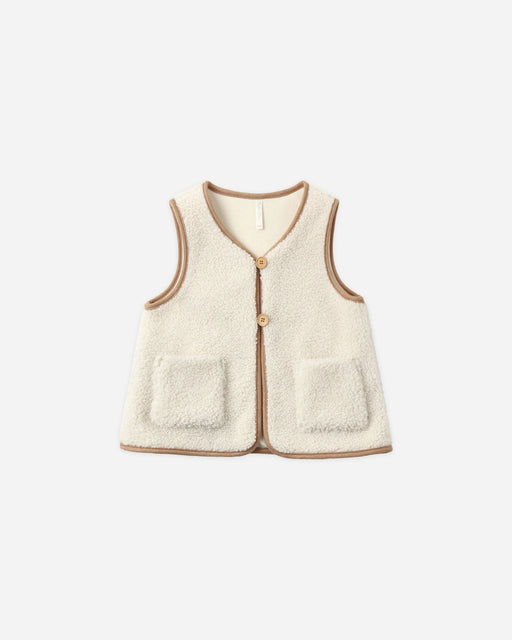 A cream-colored sherpa fleece vest with tan trim and button details, displayed flat against a light gray background.
